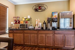 A breakfast bar with a coffee machine, juice dispenser, and various food items. - Econo Lodge Gadsden Area (Grant)