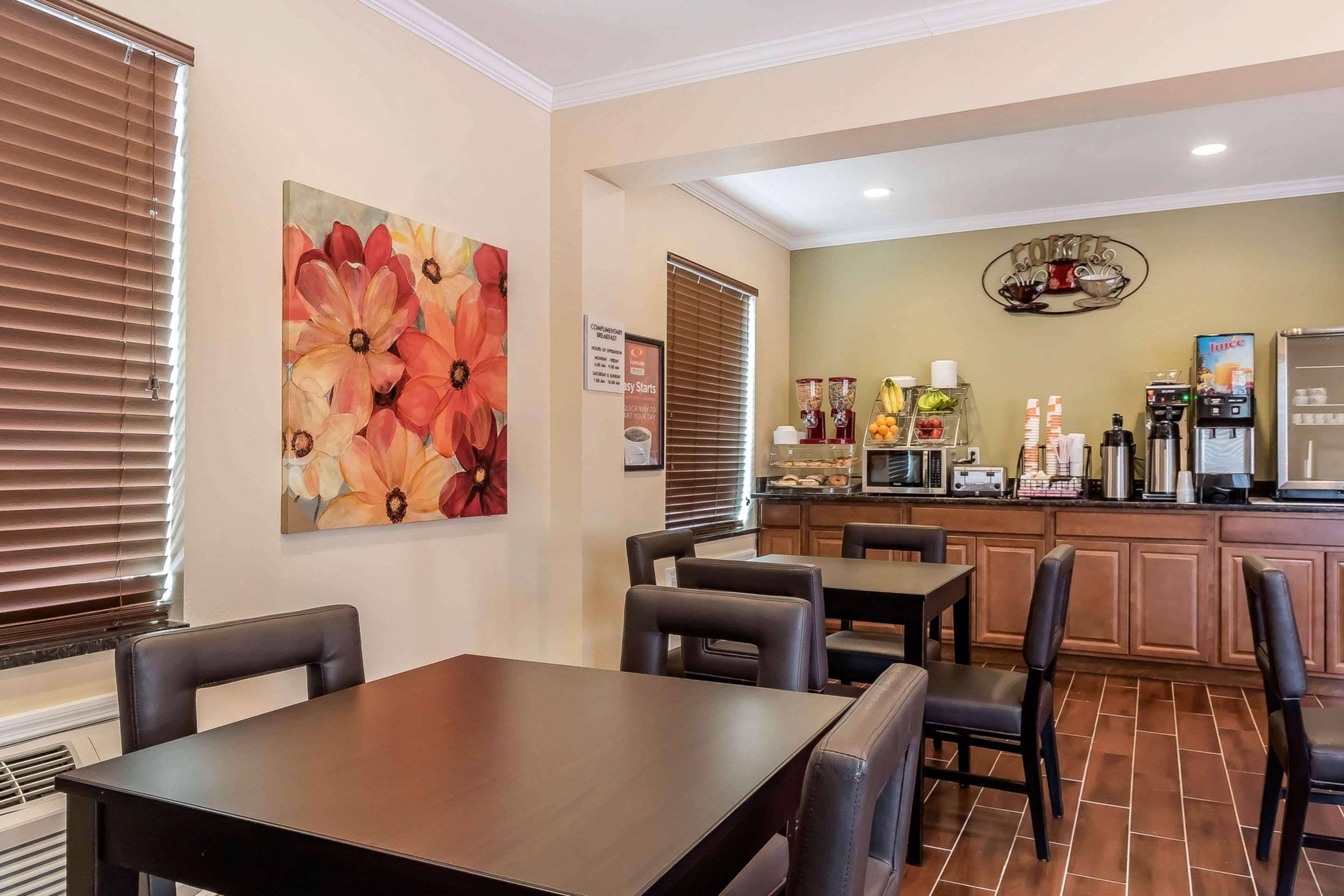 A dining area with a table and chairs, a kitchen with appliances, and a decorative wall piece.