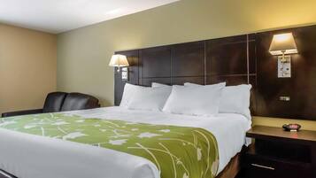 A hotel room with a large bed, two bedside lamps, a clock, and a chair.