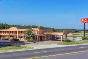A hotel with a red sign, a parking lot, and a clear sky. - Econo Lodge Gadsden Area (Grant)