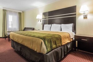 A hotel room with a large bed, two bedside lamps, a desk, and a chair. - Econo Lodge Gadsden Area (Grant)