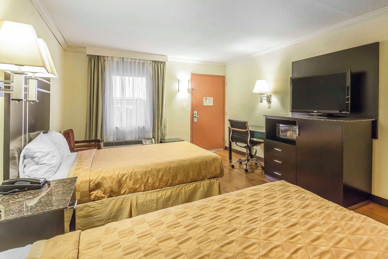 A hotel room with two beds, a desk, a television, and a wardrobe.