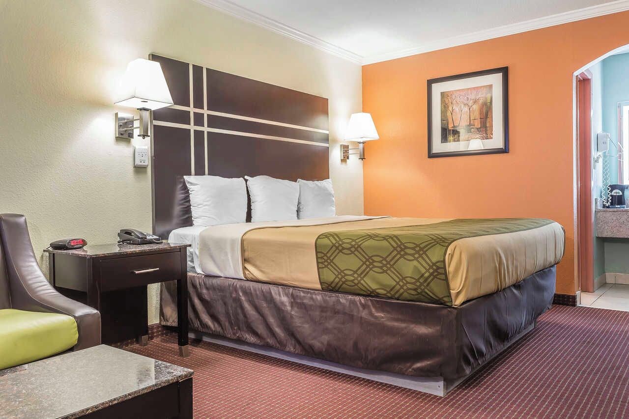 Une chambre d’hôtel avec un lit, une table de chevet, une lampe et un tableau au mur.