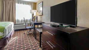 A hotel room with a bed, desk, chair, television, and a patterned carpet. - Econo Lodge Gadsden Area (Grant)