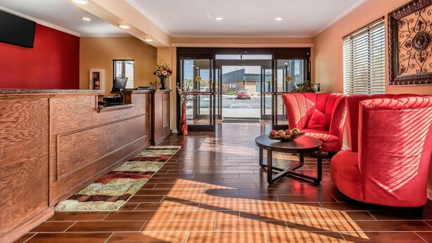 A hotel lobby with a reception desk, red seating area, and a view of the parking lot through glass doors. - Econo Lodge Gadsden Area (Grant)