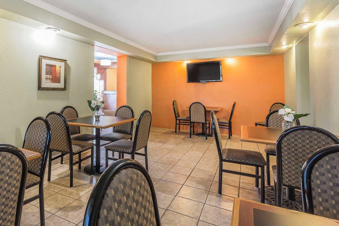 A dining area with multiple tables and chairs, a flat-screen TV mounted on the wall, and a framed picture on the wall.