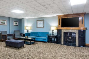 A living room with a blue sofa, two armchairs, a coffee table, and a fireplace.