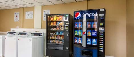 A laundromat with a Pepsi vending machine, a dryer, and a washing machine.