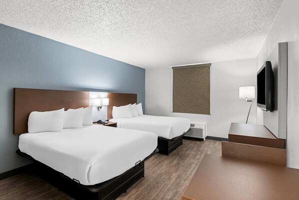 A hotel room with two beds, a flat-screen TV, a desk, and a window. - Suburban Studios Chester I-95 (Chester)