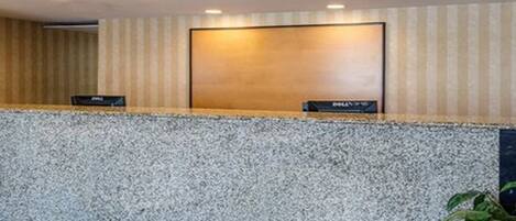 A reception desk with a clock, a nameplate, and a potted plant.