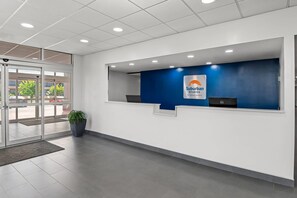 Un área de recepción con una pared azul, el letrero de Suburban Studios y una planta en maceta.