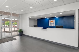 Un área de recepción con una pared azul, el letrero de Suburban Studios y una planta en maceta.