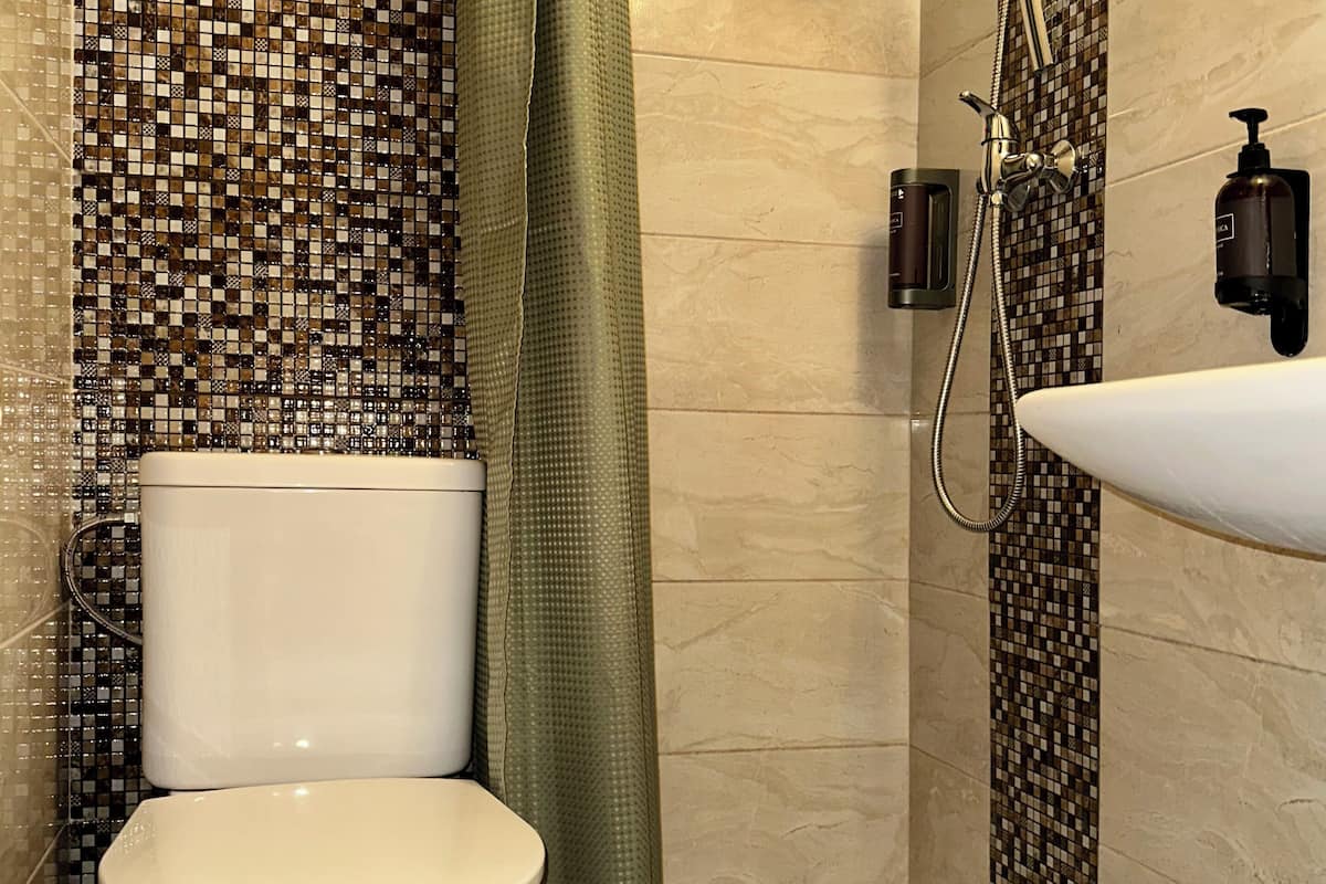 A bathroom with a toilet, shower, and sink.