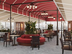 A spacious indoor area with multiple seating arrangements, including sofas and chairs, under a large red and white striped ceiling. - Botel Albatros (Prague)