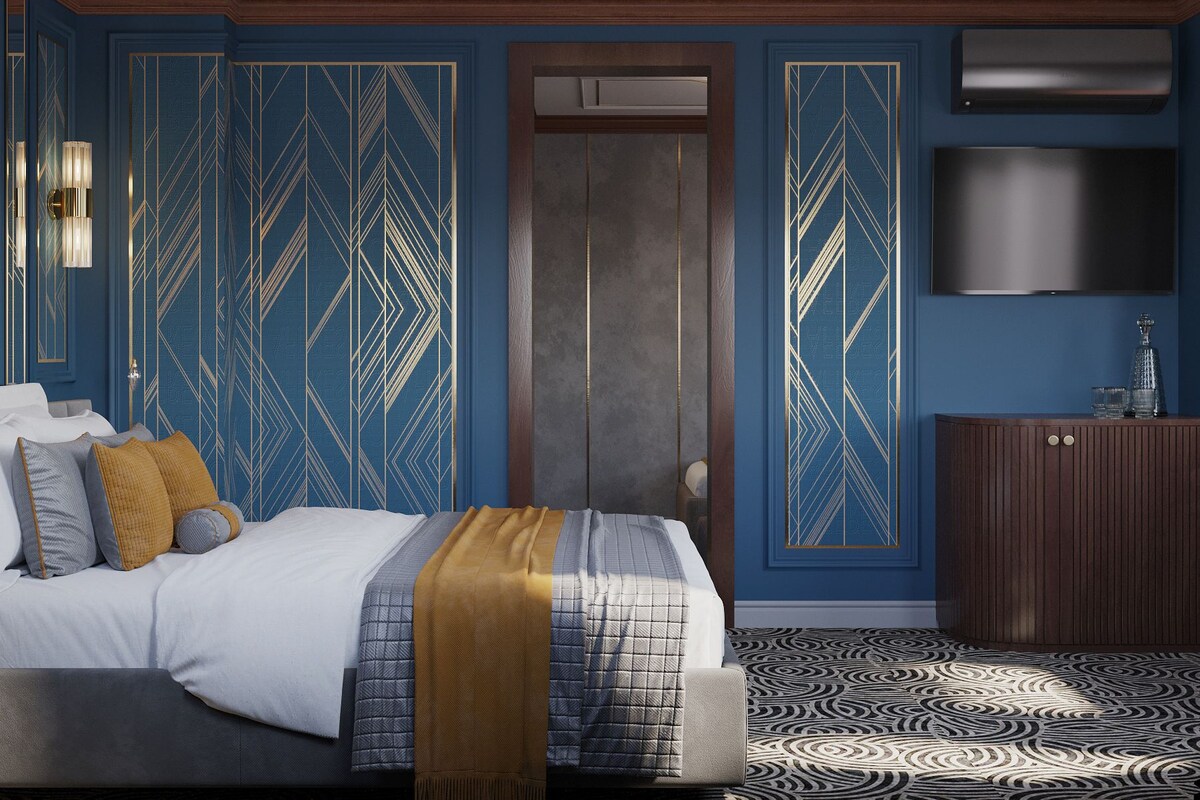 A hotel room with a large bed, a television, and a patterned rug.