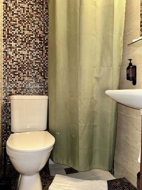 Ein Badezimmer mit Toilette, Duschvorhang, Waschbecken und Fliesen.