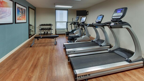 A gym with treadmills, a bench, and a rack of dumbbells. - Pear Tree Inn Airport St. Louis - St. Ann (St. Ann)