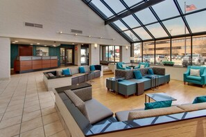 A spacious lobby with a high ceiling and large windows, featuring multiple seating areas and a reception desk. - Pear Tree Inn Airport St. Louis - St. Ann (St. Ann)