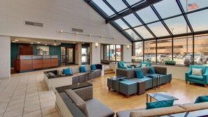 A spacious lobby with a high ceiling and large windows, featuring multiple seating areas and a reception desk. - Pear Tree Inn Airport St. Louis - St. Ann (St. Ann)