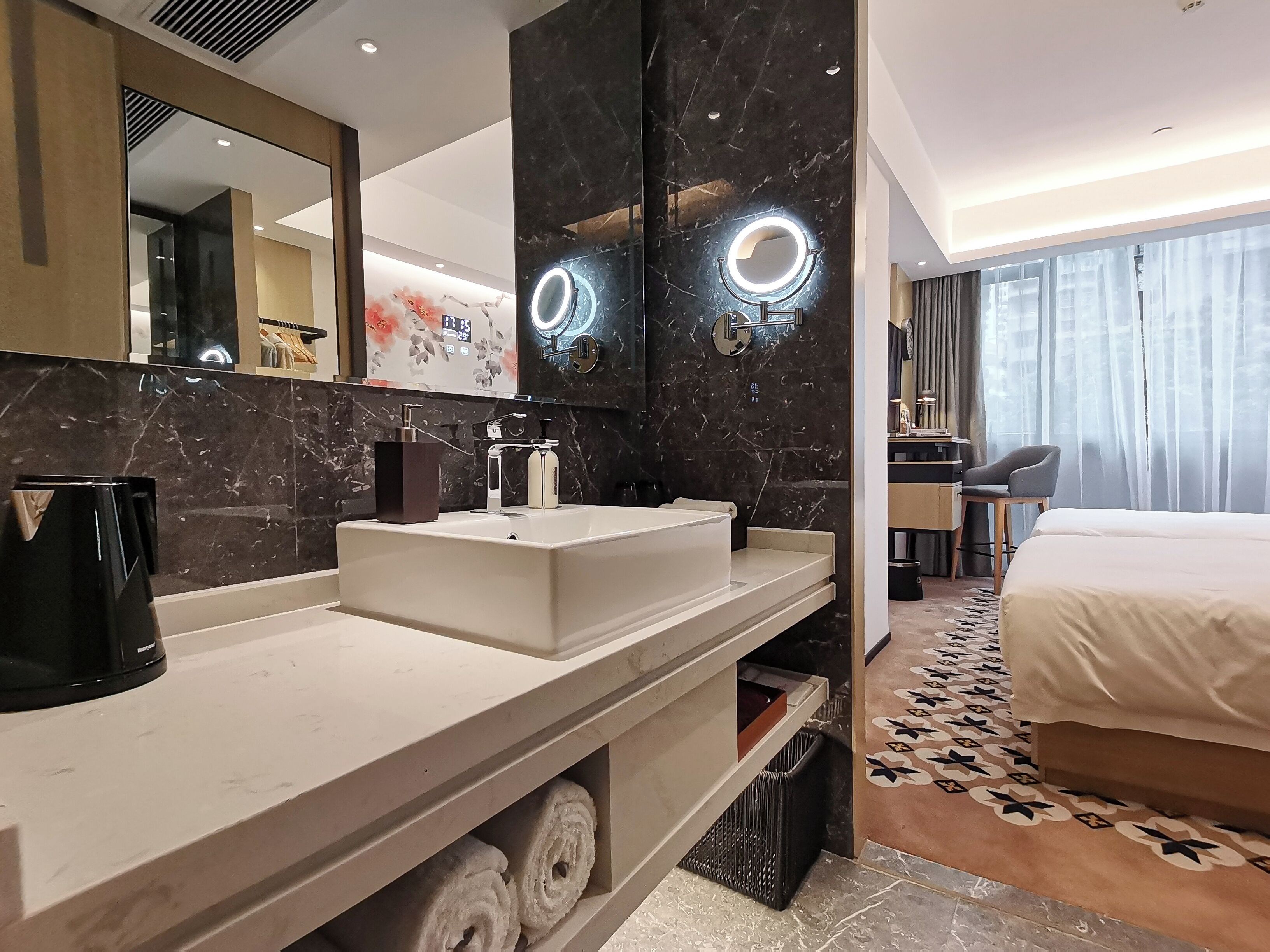 A modern hotel bathroom with a large mirror, a sink, and a vanity.