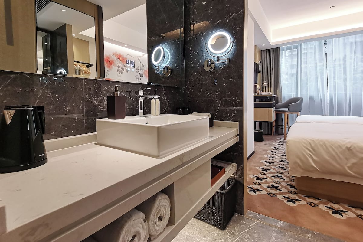 A modern hotel bathroom with a large mirror, a sink, and a vanity.