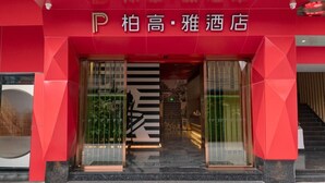 The entrance to a hotel with a red facade and a glass door.