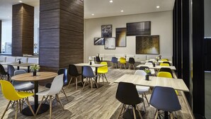 A modern dining area with round tables and colorful chairs, a wooden accent wall, and artwork on the walls. - Contemporaneo (Campinas)