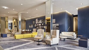 A modern lobby with a geometric carpet design, contemporary seating arrangements, and a large mirror reflecting the space. - Contemporaneo (Campinas)