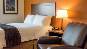 A hotel room with a bed, a chair, a nightstand with a lamp, and a framed picture on the wall. - My Place Hotel-marquette, MI (Marquette)
