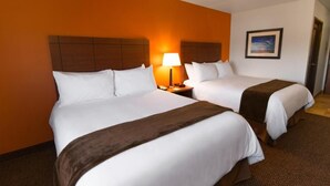 A hotel room with two beds, a nightstand with a lamp, and a framed picture on the wall. - My Place Hotel-marquette, MI (Marquette)