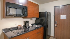 A compact kitchen with a microwave, coffee maker, refrigerator, and wooden cabinets. - My Place Hotel-marquette, MI (Marquette)