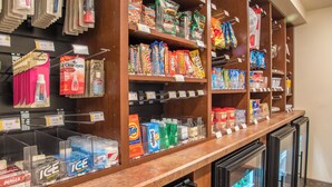A self-service beverage station with refrigerated drink dispensers and a variety of packaged snacks and toiletries. - My Place Hotel-marquette, MI (Marquette)