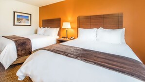A hotel room with two beds, a nightstand with a lamp, and a framed picture on the wall. - My Place Hotel-marquette, MI (Marquette)