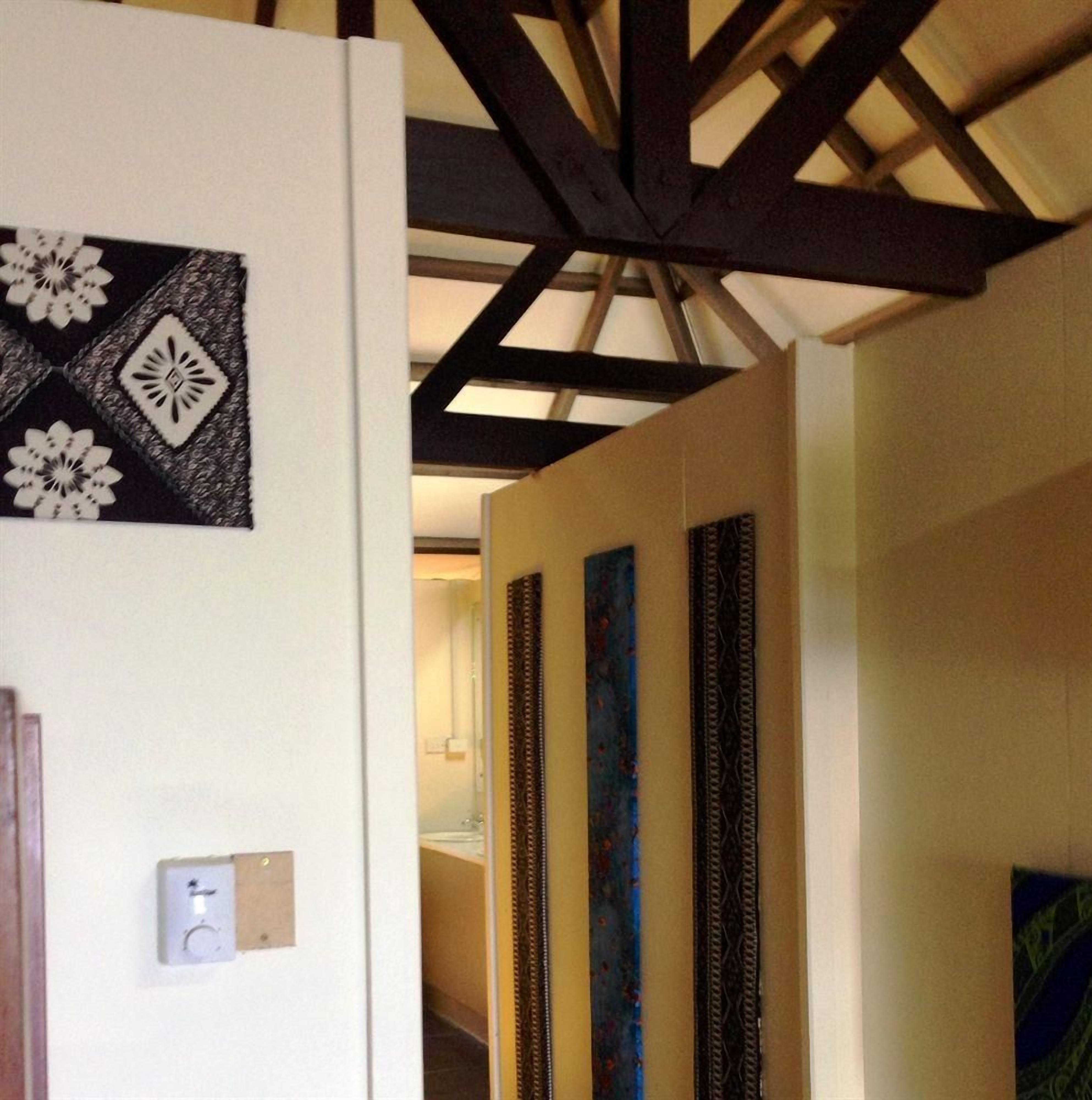 A hallway with a white wall, a black and white patterned artwork, and a light switch.