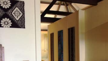 A hallway with a white wall, a black and white patterned artwork, and a light switch.