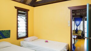 Une chambre avec deux lits, une fenêtre et une vue sur une autre chambre.