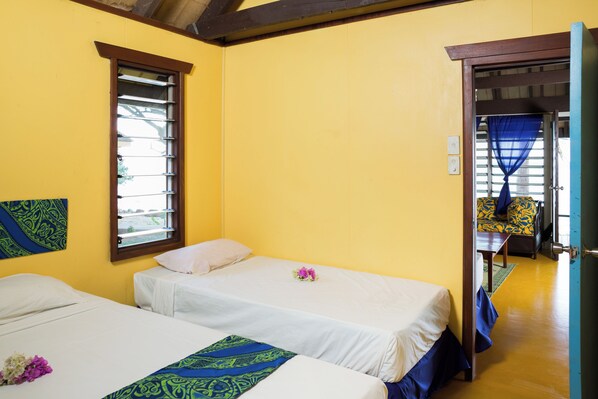 A room with two beds, a window, and a view of another room. - Funky Fish Beach Resort (Malolo Island)