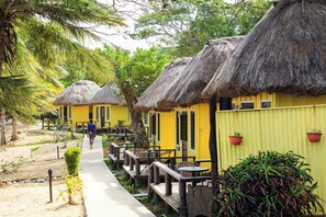 A row of yellow buildings with thatched roofs, wooden benches, and potted plants. - Funky Fish Beach Resort (Malolo Island)