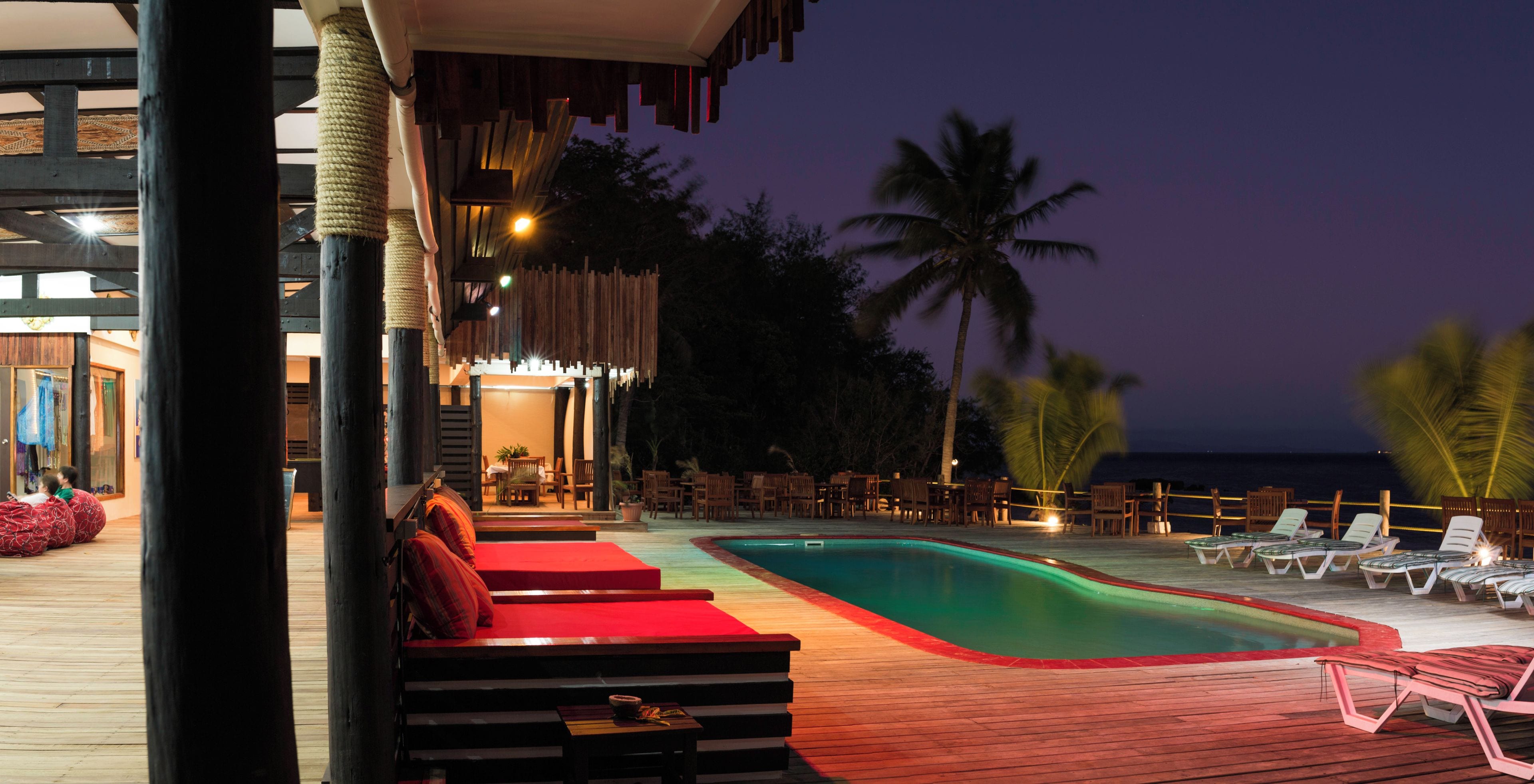 Zona de piscina con sillones de descanso y un área de estar roja.