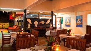 Un restaurant avec des tables et des chaises en bois, un plafond en bois et des œuvres d’art accrochées aux murs.