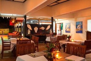 A restaurant with wooden tables and chairs, a wooden ceiling, and wall-mounted artwork. - Funky Fish Beach Resort (Malolo Island)