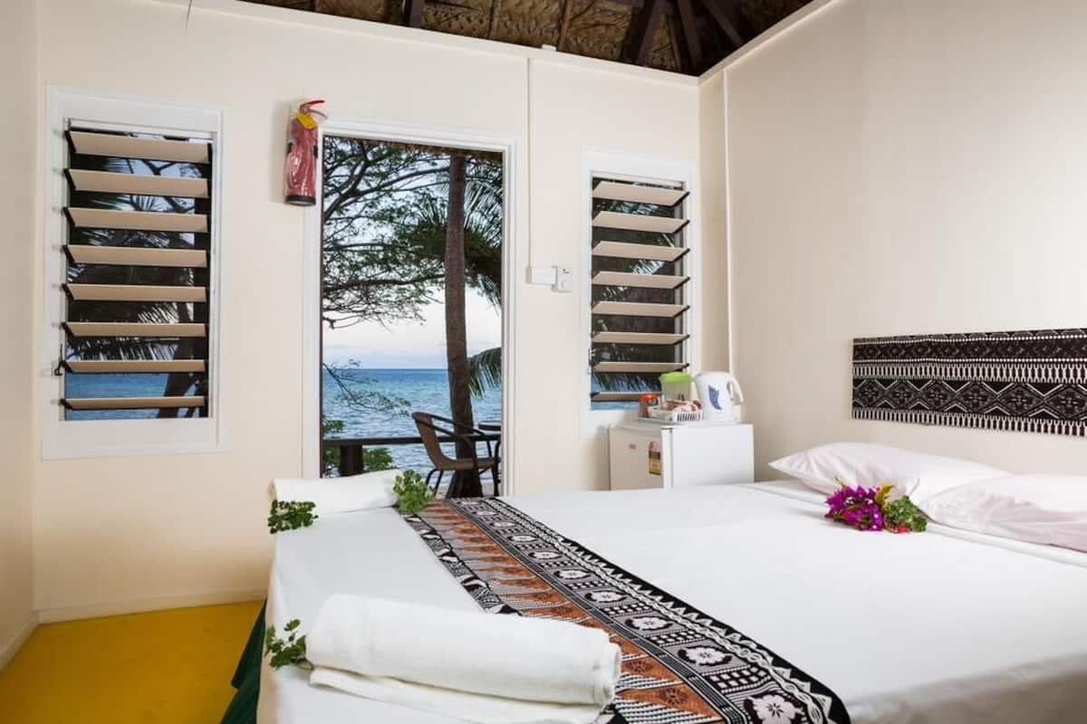 Ein Schlafzimmer mit Bett, Meerblick und Fenster mit Rollläden.
