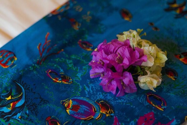 A tablecloth with a blue background and colorful fish patterns, a bouquet of pink and white flowers, and a small fish decoration. - Funky Fish Beach Resort (Malolo Island)