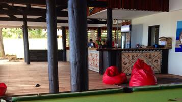 A pool area with a bar, red bean bags, and a television on the wall.