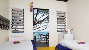 A room with two beds, a desk, and a view of the beach through a door. - Funky Fish Beach Resort (Malolo Island)