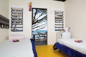 A room with two beds, a desk, and a view of the beach through a door. - Funky Fish Beach Resort (Malolo Island)