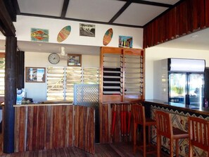 A bar area with wooden furniture, a clock, and various wall decorations. - Funky Fish Beach Resort (Malolo Island)