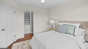 Une chambre à coucher comprenant un lit, une table de chevet, une lampe, un ventilateur de plafond et un placard.