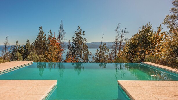 Ein klares Schwimmbecken mit Blick auf Bäume und Berge im Hintergrund.