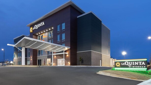 A modern hotel with a covered entrance, a prominent sign, and a well-lit facade. - La Quinta Inn & Suites by Wyndham Athens I-65 (Athens)